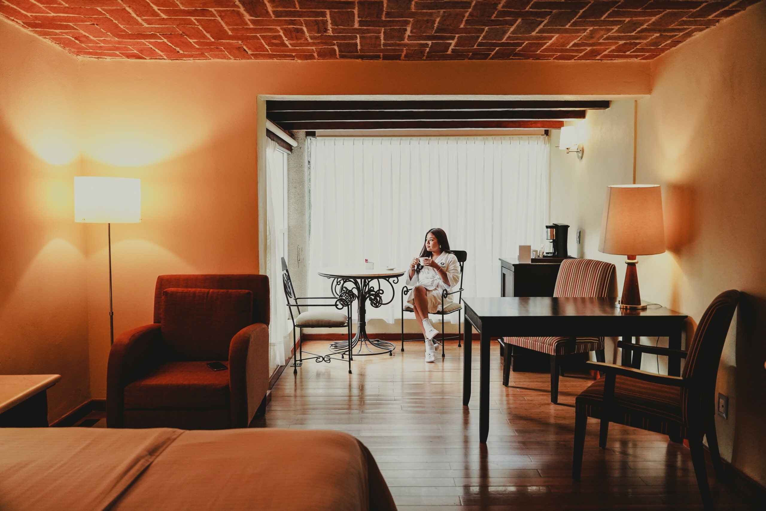 Huésped disfrutando un café por la mañana en una habitación con techo de ladrillo