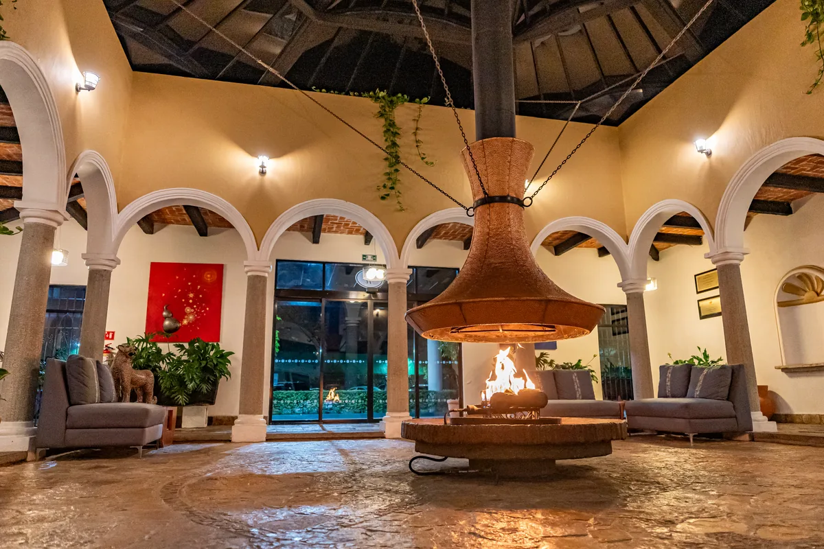 Patio de arcos con la chimenea de cobre encendida al anochecer